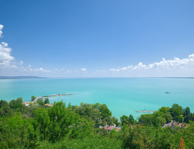 View of Balaton lake, Hungary, with green hill of Tihany city on foreground, with crystal clear water of emerald color and some clouds on the skyline